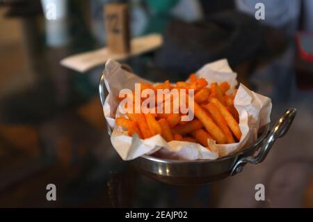 Hand holding French fries with chili cheese powder in a pan Stock Photo