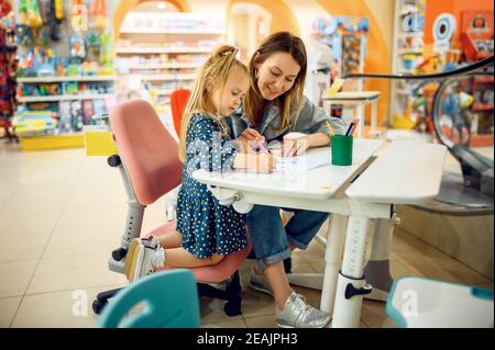 Mother and little baby draws in kid's store Stock Photo