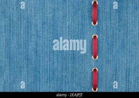 Red silk ribbon is inserted in a light denim fabric. With place for your text. Stock Photo