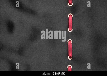 Red ribbon are inserted in a black wavy satin. Fashionable beautiful background. Stock Photo