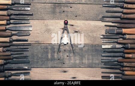 Many firmer chisels as frame on a rustic workbench Stock Photo