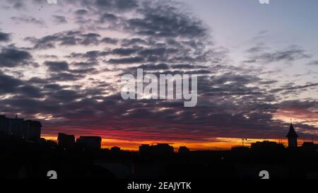 Cloudy fire sunrise with backlit buildings and cloudy sky. Landscape of fire sunrise Stock Photo