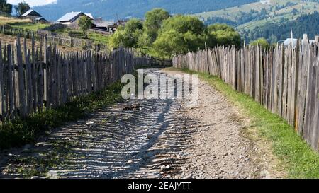 Road with ballast in the mountains with houses - fence in the mountains Stock Photo