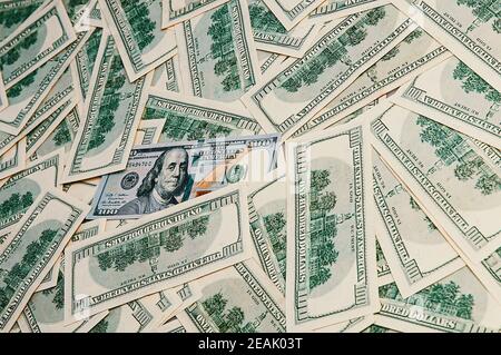 Background from dollars. Notes of one hundred American dollars are scattered across the background Stock Photo