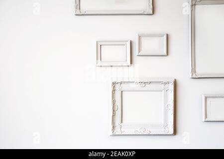 White various antique blank photo or picture frames on the white wall modern design, minimal interior design, copy space or space for text Stock Photo