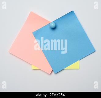 stack of colorful stickers pinned by blue button on white background Stock Photo