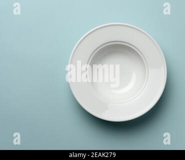 empty white ceramic plate on blue background Stock Photo