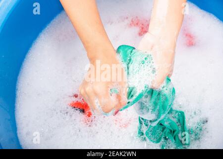 Woman use hands washing color clothes in basin Stock Photo