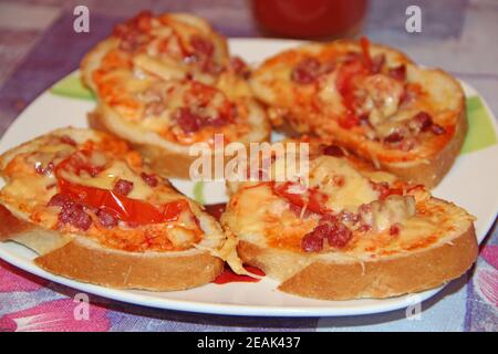 hot sandwiches with sausage and melted cheese on plate Stock Photo
