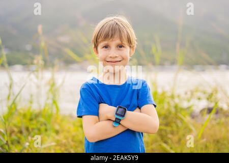 Boy uses kids smart watch outdoor against the background of the garden Stock Photo