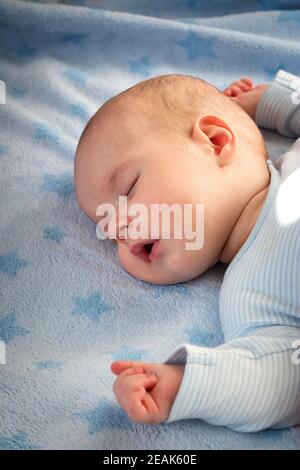 three month old baby sleeping on blue blanket Stock Photo