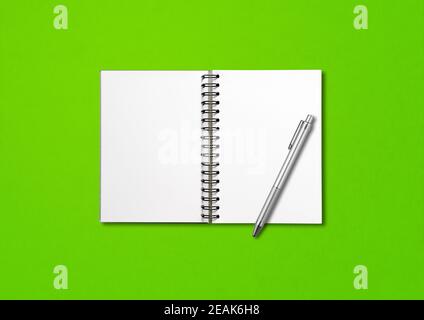 Blank open spiral notebook and pen isolated on green Stock Photo