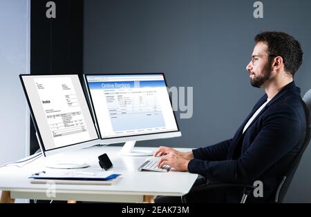 Young Businessman Looking At Invoice While Doing Online Banking Stock Photo