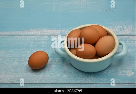 Bowl of brown chicken eggs on blue table Stock Photo
