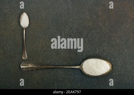 Two spoons of sugar and salt on table Stock Photo