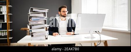 Young Businessman Working At Office With Stack Of Folders Stock Photo