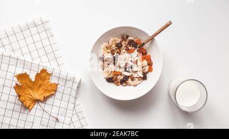 Carbohydrate healthy breakfast. Oatmeal with dried fruits on a white plate. View from above Stock Photo