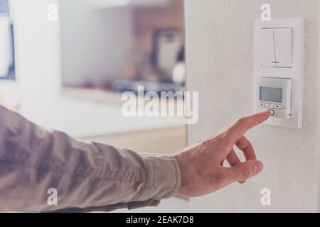 Men hand setting the temperature on control panel of DHW or central heating Stock Photo