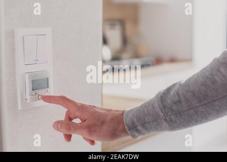 Men hand setting the temperature on control panel of DHW or central heating. Stock Photo