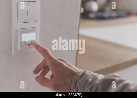 Men hand setting the temperature on control panel of DHW or central heating. Stock Photo