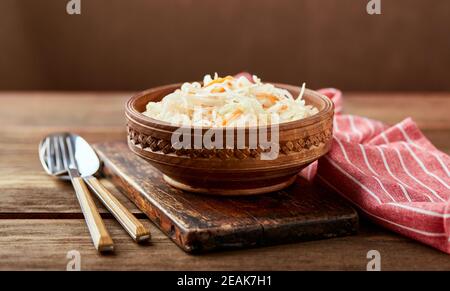 Sauerkraut, fermented cabbage with carrots in bowl on wooden background. Superfoods for support the immune system. Stock Photo