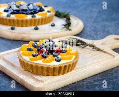 Blueberry and mixed fruit cheesecake pie on wooden cutting board. Stock Photo
