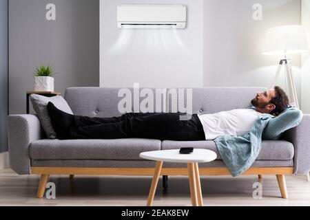 Happy Man Relaxing And Enjoying Cool Air Conditioner Stock Photo