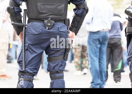 Riot police officer holding hand on his gun during street protest Stock Photo