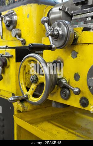 Old yellow lathe machine with a lot of handles. Stock Photo