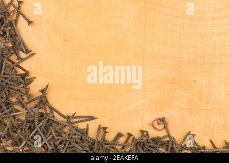 Frame of new black screws lying on a wooden surface. Stock Photo