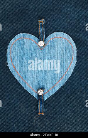 Frame made of jeans in the shape of a heart, lies on a denim fabric. Stock Photo