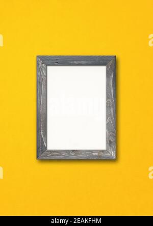 Old rustic wooden picture frame hanging on a yellow wall Stock Photo