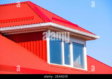 House with plastic windows and a red roof of corrugated sheet Stock Photo