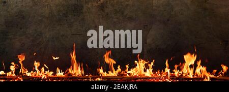 Fire flames in front of dark concrete wall Stock Photo