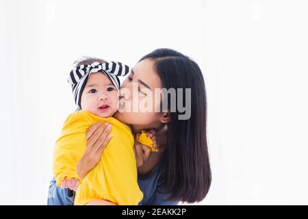 mother kissing her infant newborn baby in a white bed Stock Photo