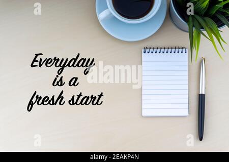 EVERYDAY IS A FRESH START text with fountain pen, notepad, decorative flower and cup of coffee on wooden background Stock Photo