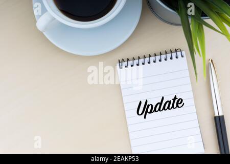 UPDATE text with fountain pen, notepad, decorative flower and cup of coffee on wooden background Stock Photo