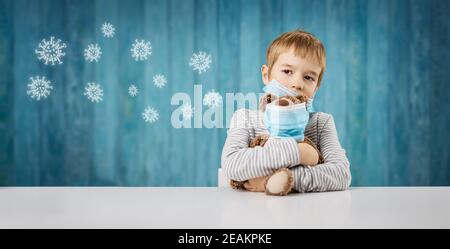 little boy sitting with a teddy bear in medical facial masks Stock Photo