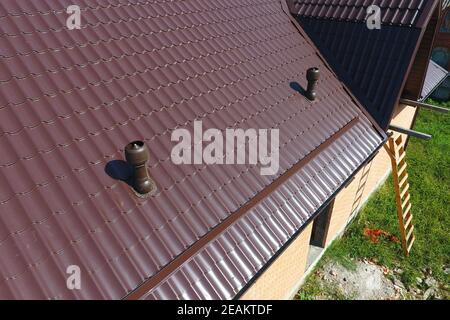 Air ducts on metal roof. The roof of corrugated sheet. Roofing of metal profile wavy shape Stock Photo