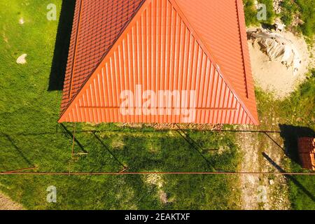 House with an orange roof made of metal, top view. Metallic profile painted corrugated on the roof. Stock Photo