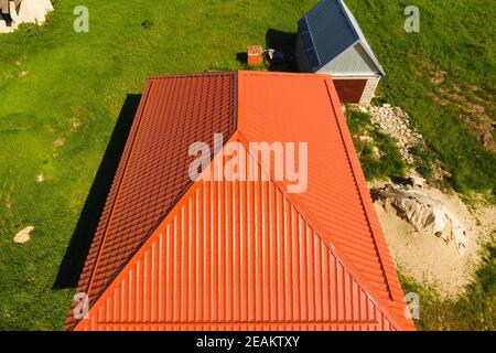 House with an orange roof made of metal, top view. Metallic profile painted corrugated on the roof. Stock Photo