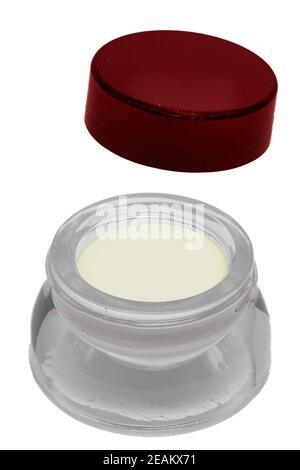 Closeup of an open glass cosmetic jar with a moisturising white cream for the face isolated on a white background. Beauty and make-up products. Stock Photo