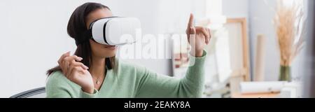 african american architect pointing with finger while gaming in vr headset at home, banner Stock Photo