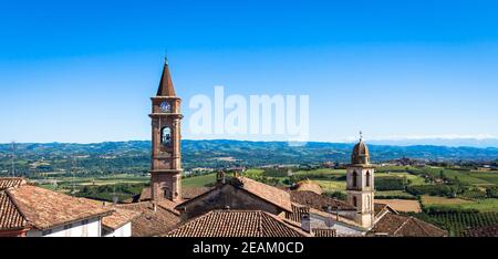 Piedmont hills in Italy with scenic countryside, vineyard field and blue sky. Govone bell tower on the left. Stock Photo
