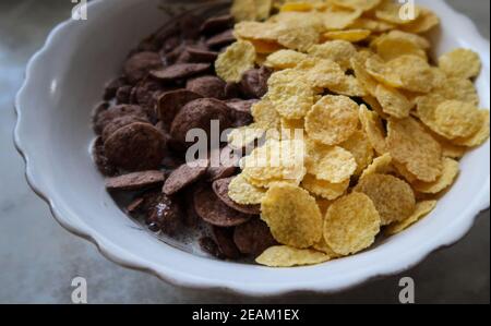 Bowl of black and yellow cereals on grey background side view Stock Photo