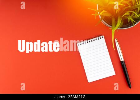 UPDATE text with laptop, fountain pen and decorative plant on red background. Stock Photo