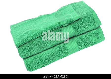 Towels isolated. Closeup of a stack or pile of green soft terry bath towels isolated on a white background. Stock Photo