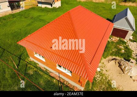 House with an orange roof made of metal, top view. Metallic profile painted corrugated on the roof. Stock Photo