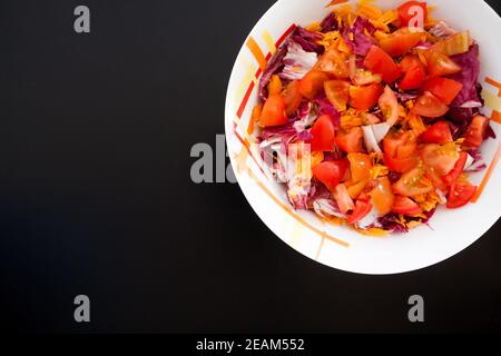 Salad with carrots and tomatoes on black table, top view Stock Photo