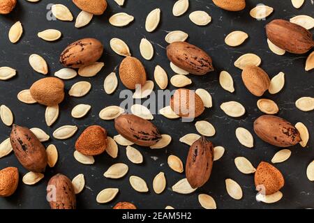 Whole almonds, pecan nuts and pumpkin seeds mixed on black marble like board, view from above Stock Photo